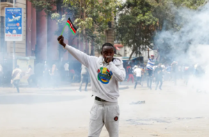 A man holds up a flag of Kenya as police use tear gas to disperse protesters during a demonstration in Nairobi, Kenya 